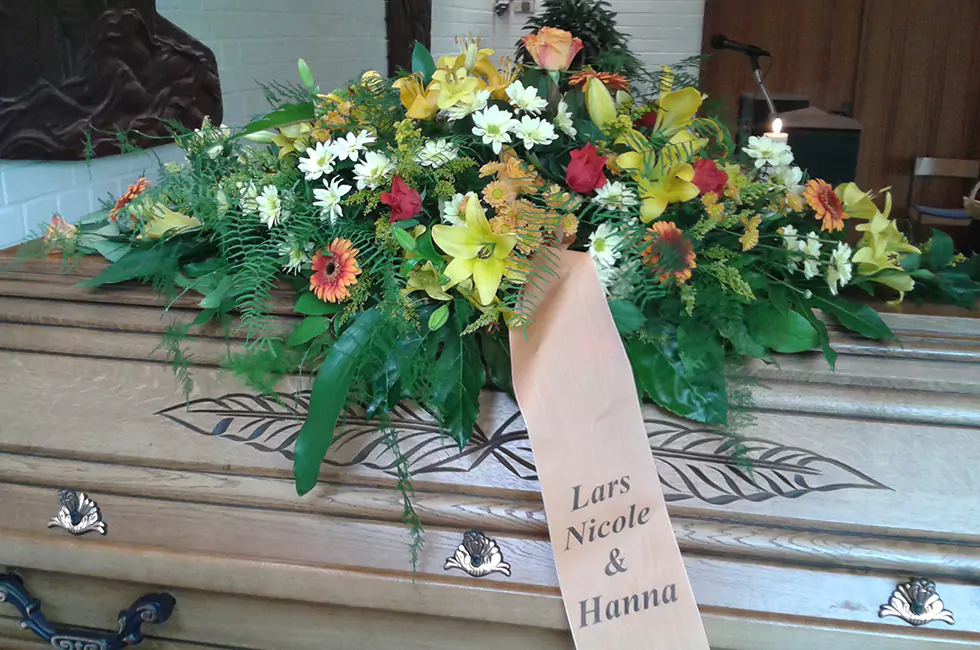 Nahaufnahme Blumengesteck auf Holzsarg