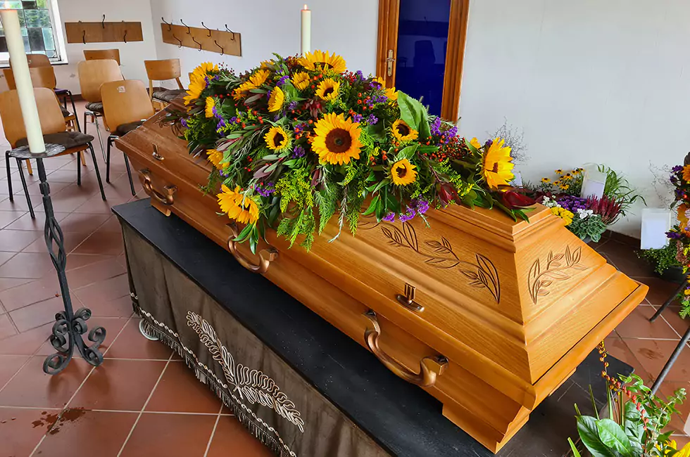 Sonnenblumen auf Holzsarg bei Bestattungsfeier