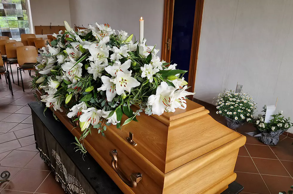 Lilien auf Holzsarg bei Bestattungsfeier