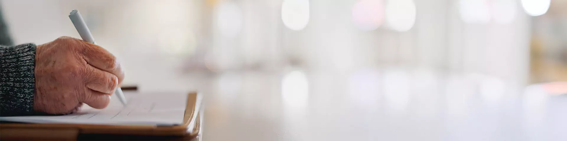 Hand, die die Unterlagen zur Bestattungsvorsorge unterschreibt