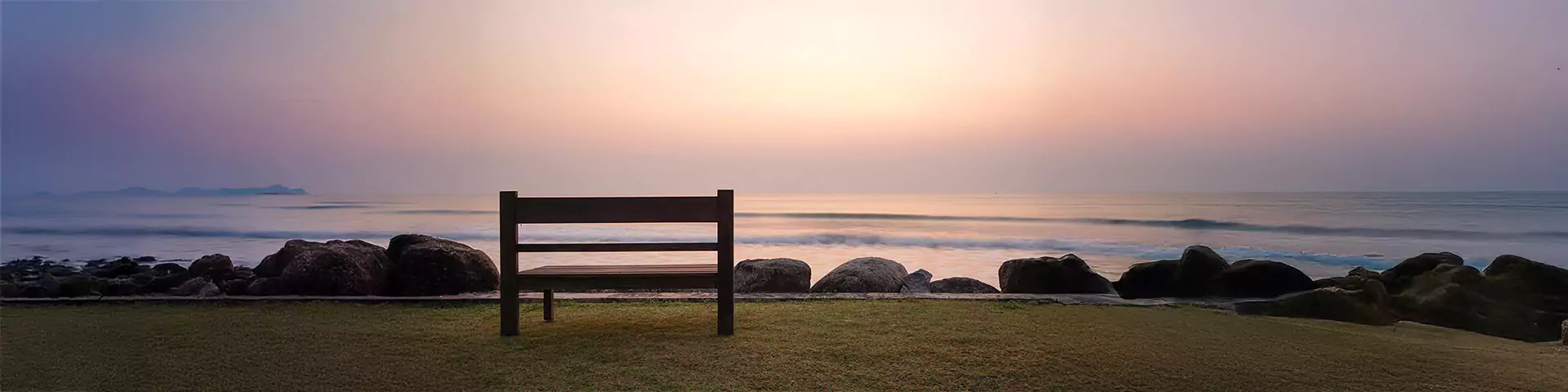 Einsame Bank vor Sonnenaufgang am Meer
