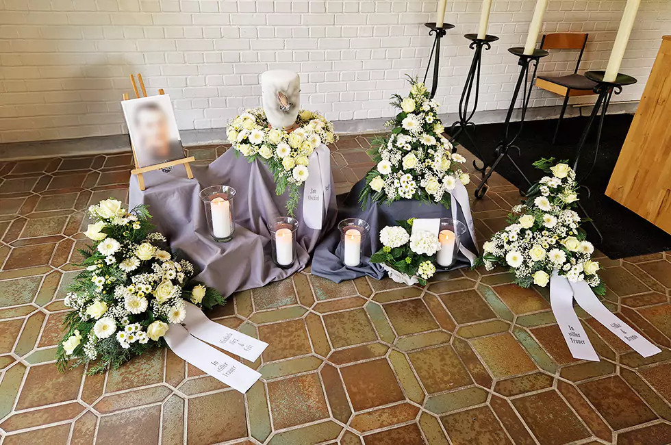 Weiße Urne und weiße Blumen bei Trauerfeier