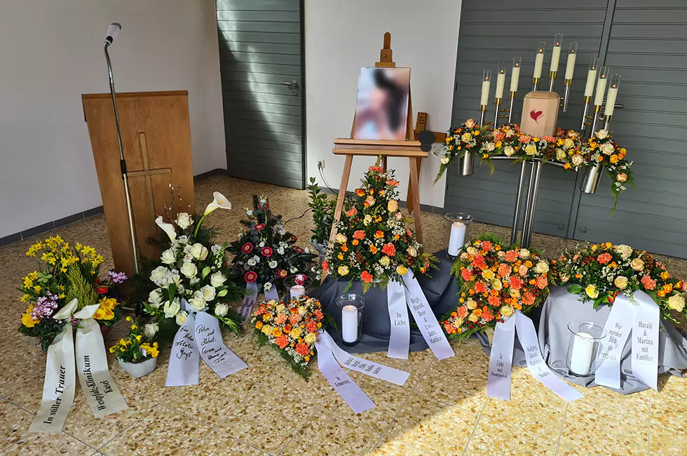 Beige Urne und bunte Blumen bei Trauerfeier