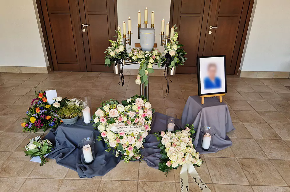 Graue Urne und weiße Blumen bei Trauerfeier