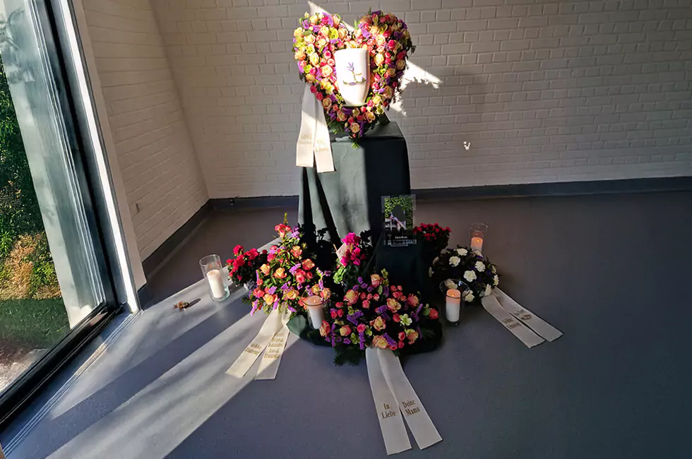 Weiße Urne und bunte Blumen bei Trauerfeier